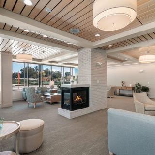 A modern lounge area with a central fireplace, comfortable seating, and large windows allowing natural light to fill the space.