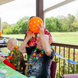 Seniors enjoying a festive outdoor party with colorful balloons and decorations.