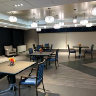 A modern dining area with neatly arranged tables and chairs, illuminated by stylish overhead lighting.