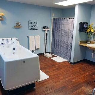 A hydrotherapy treatment room with a bathtub, scale, and sink.