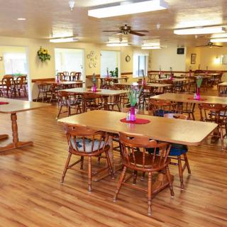 A spacious dining area with wooden tables and chairs, decorated with plants.