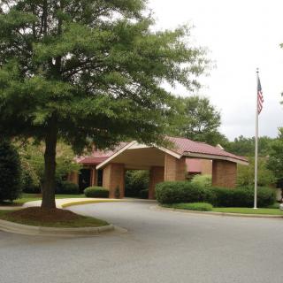 Entrance to a brick building surrounded by trees and landscaping.