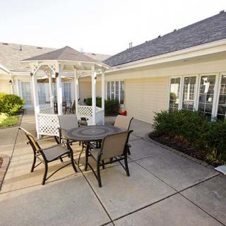 A sunny outdoor patio featuring a table and chairs next to a white gazebo.