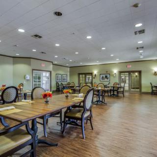 A spacious dining area with elegant tables and chairs, featuring warm lighting and wooden floors.