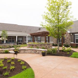 A beautifully landscaped courtyard with pathways and lush greenery in front of a modern building.