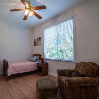 A cozy bedroom with a single bed, armchair, and large window allowing natural light.