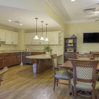 A modern kitchen and dining area featuring wooden furniture, pendant lighting, and a wall-mounted television.