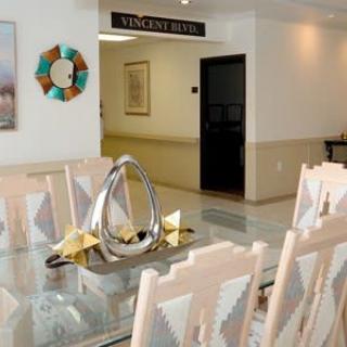 A modern dining room with a glass table and decorative centerpiece, featuring artistic elements on the walls.