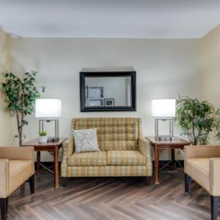 A cozy living room setup featuring a plaid sofa, armchairs, side tables with lamps, and decorative plants.