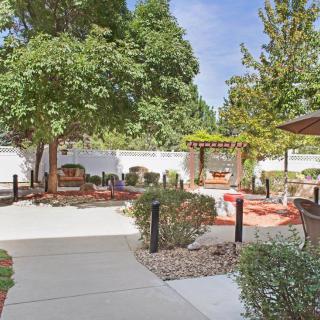 A beautifully landscaped garden with outdoor seating, featuring trees and a sunny patio area.
