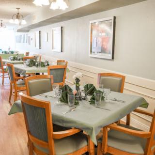 A cozy dining area with neatly set tables and wooden chairs, decorated in a soft palette.
