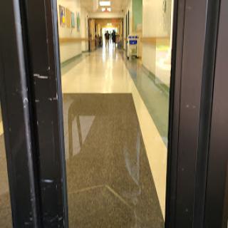 A view of a hallway through open doors, showcasing the smooth floor and distant figures.