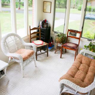A cozy sunroom featuring wicker furniture and large windows.