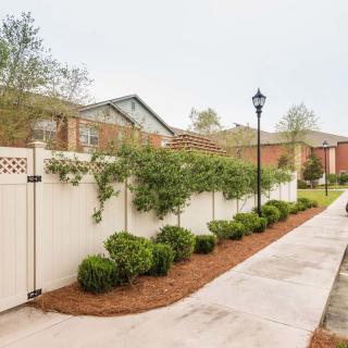 A residential area with a neatly landscaped pathway featuring shrubs and a white fence.