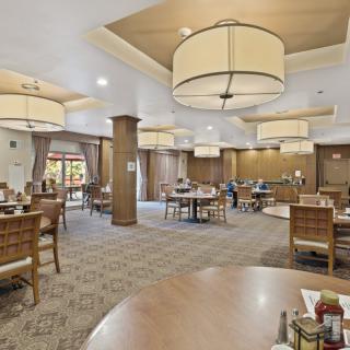 A spacious dining area with tables and chairs, elegantly lit by large overhead lights.