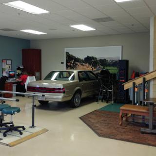 A physical therapy room featuring a car as part of the rehabilitation equipment.