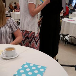 A gathering with guests enjoying conversation at tables, featuring a cup of coffee.