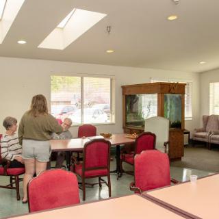 A bright and welcoming common area in a residential facility, featuring individuals engaged in conversation around a table.