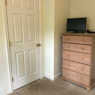 A cozy bedroom corner with a wooden dresser and a small television next to a closed door.