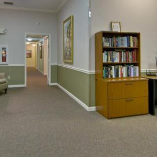 A waiting room with a bookshelf and a hallway leading to other rooms.