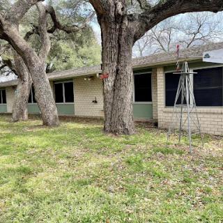 A peaceful residential setting featuring a house nestled among large trees and a grassy yard.