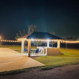 A well-lit gazebo surrounded by string lights, set on a lawn during nighttime.