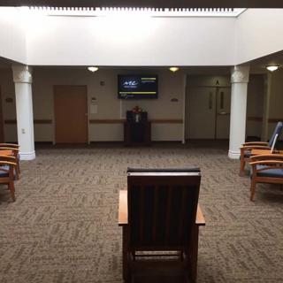 A sparse waiting area with chairs and a television on the wall.