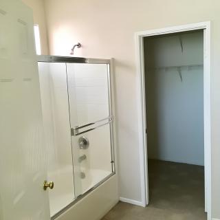 A bathroom featuring a glass-enclosed shower and an adjoining closet.
