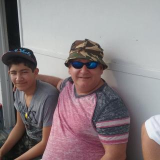 Two people sitting together casually, one wearing a camouflage hat and sunglasses.