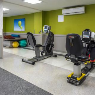 A small fitness room with exercise equipment including recumbent bikes and therapy balls.
