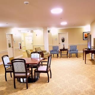 A cozy lounge area with tables and chairs, well-lit with warm lighting.