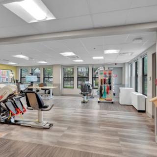 A modern gym with various exercise equipment and bright lighting.