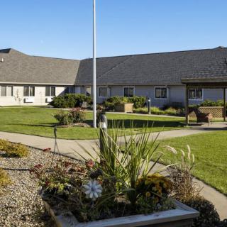 A courtyard featuring landscaped gardens and a central walkway under a clear, sunny sky.