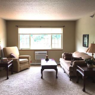 A cozy living room with a sofa, armchair, and coffee table facing a large window.