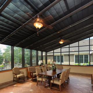A spacious sunroom featuring a dining area with large windows and ceiling fans.