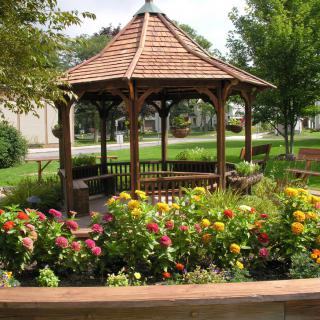 A serene garden with a wooden gazebo surrounded by colorful flowers.