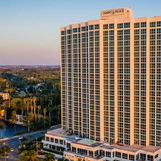 A tall hotel building stands prominently in the city at sunset.