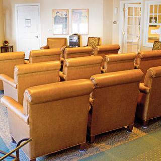 A cozy theater room with rows of comfortable leather chairs arranged for viewing.