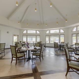 A spacious dining area with elegant tables and chairs, featuring abundant natural light through large windows.