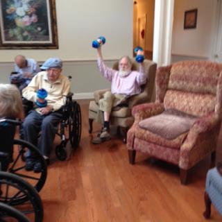 Elderly individuals participating in a fitness session, using dumbbells for exercise.