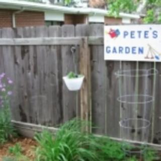 A wooden fence with a sign reading 'Pete's Garden' and surrounding greenery.