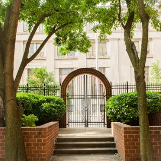 A serene entrance framed by lush trees and greenery, inviting you into a peaceful space.