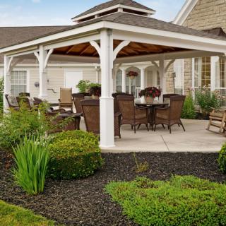 A charming outdoor gazebo with seating area surrounded by a landscaped garden.