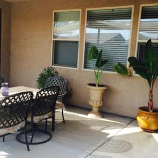 A cozy patio featuring a dining set and potted plants against a house wall.