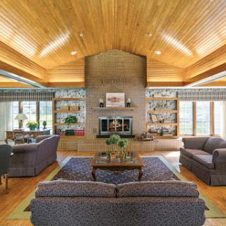 A contemporary living room featuring a wooden ceiling, a cozy fireplace, and inviting seating arrangements.