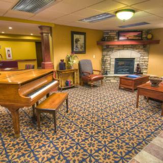 A cozy living room with a grand piano and a fireplace.