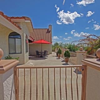 A sunny patio with a red umbrella, surrounded by desert landscape.
