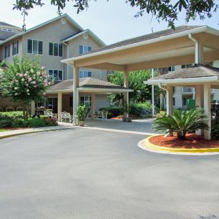 A well-maintained building entrance with a covered driveway and landscaped surroundings.