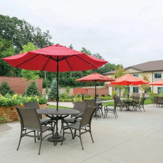 Outdoor patio area with tables, chairs, and red umbrellas.