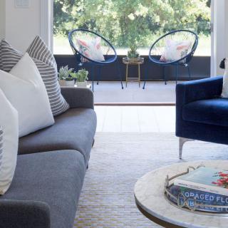 A modern living room with stylish furniture and a view of outdoor seating.